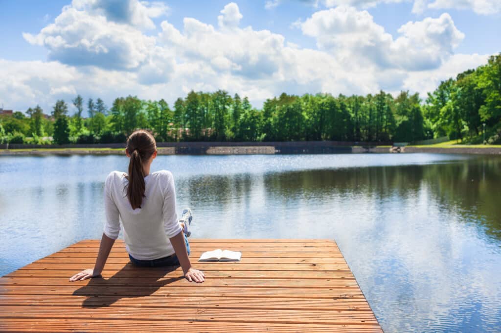 woman relaxing by a lake after experiencing panic attack symptoms