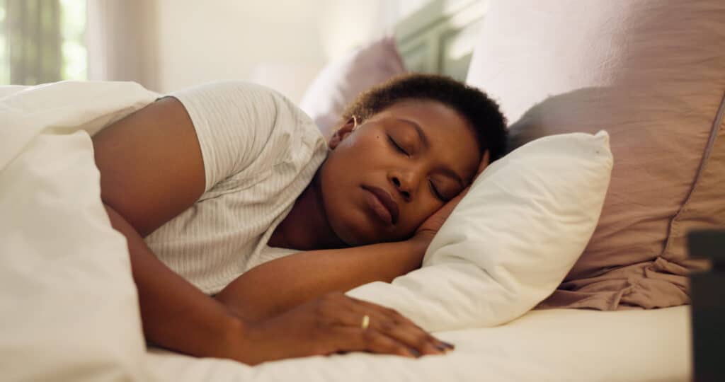 Tired, dream and black woman with sleeping in bed for resting, peaceful and comfortable on pillow; anxiety and sleep