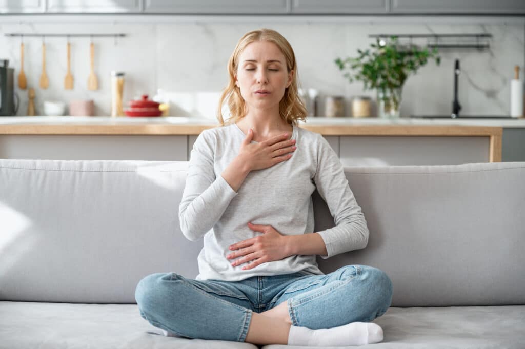 advanced breathing techniques to stop a panic attack - Woman doing calming breathing exercises after panic attack