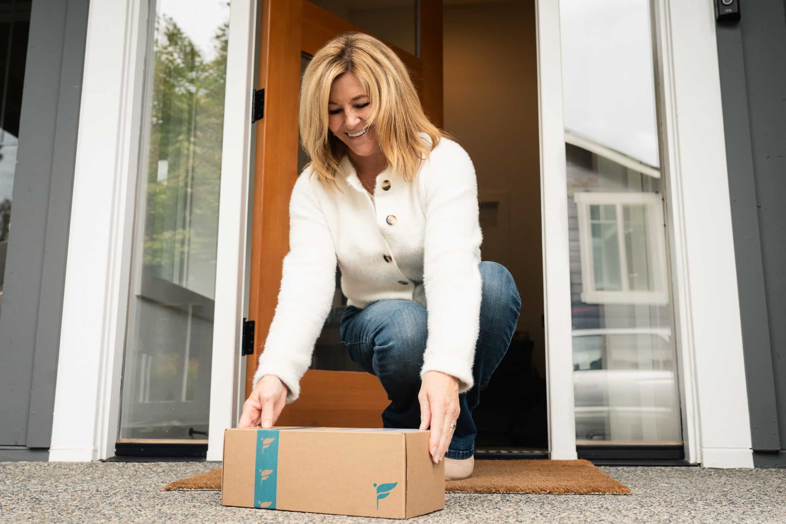 Woman grabbing the Freespira box from her doorstep after delivery