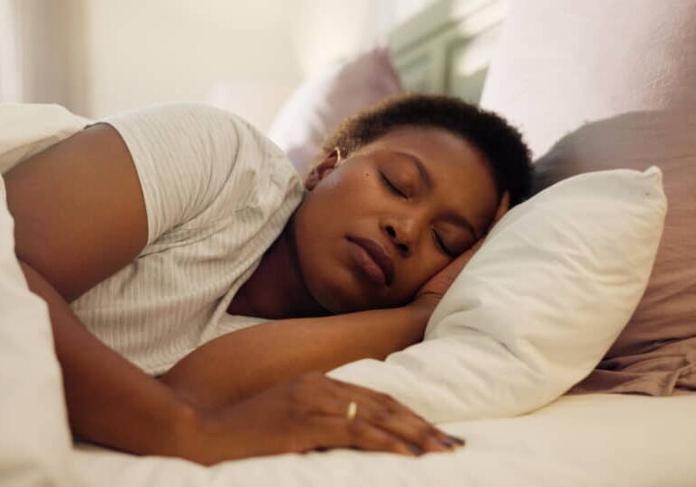 Tired, dream and black woman with sleeping in bed for resting, peaceful and comfortable on pillow; anxiety and sleep