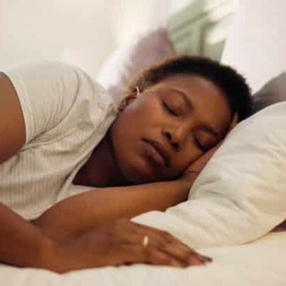 Tired, dream and black woman with sleeping in bed for resting, peaceful and comfortable on pillow; anxiety and sleep