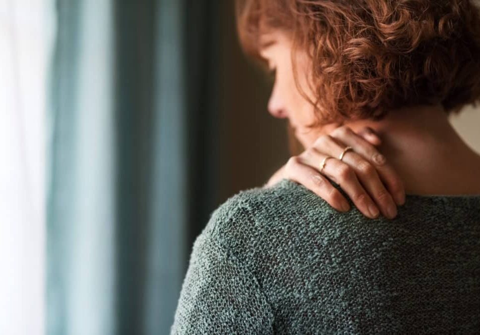Rear view shot of a woman suffering from a shoulder pain