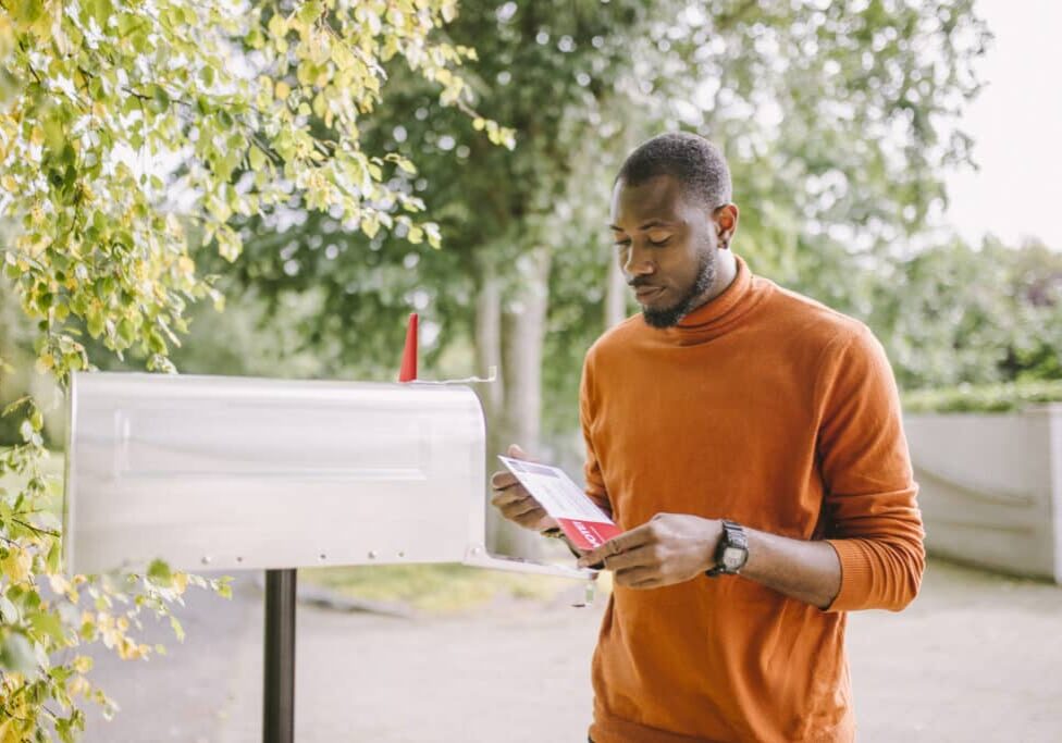 Portrait of African-American man receiving mail-in voting ballot.