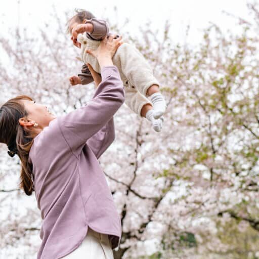 A mother and her small daughter are enjoying their time during spring time sakura cherry blossom trees season in nature.