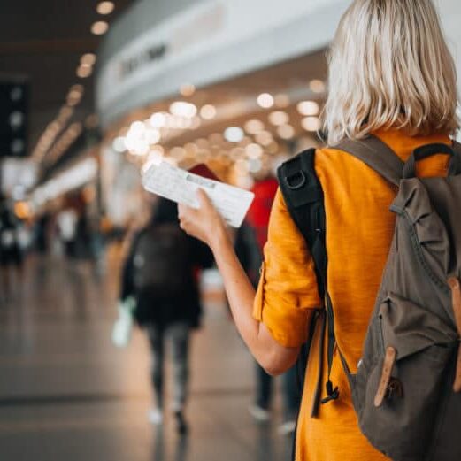 A woman at the airport holding a passport with a boarding pass