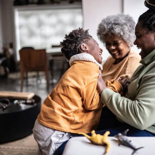 Child playing with his mother and grandmother in the living room at home