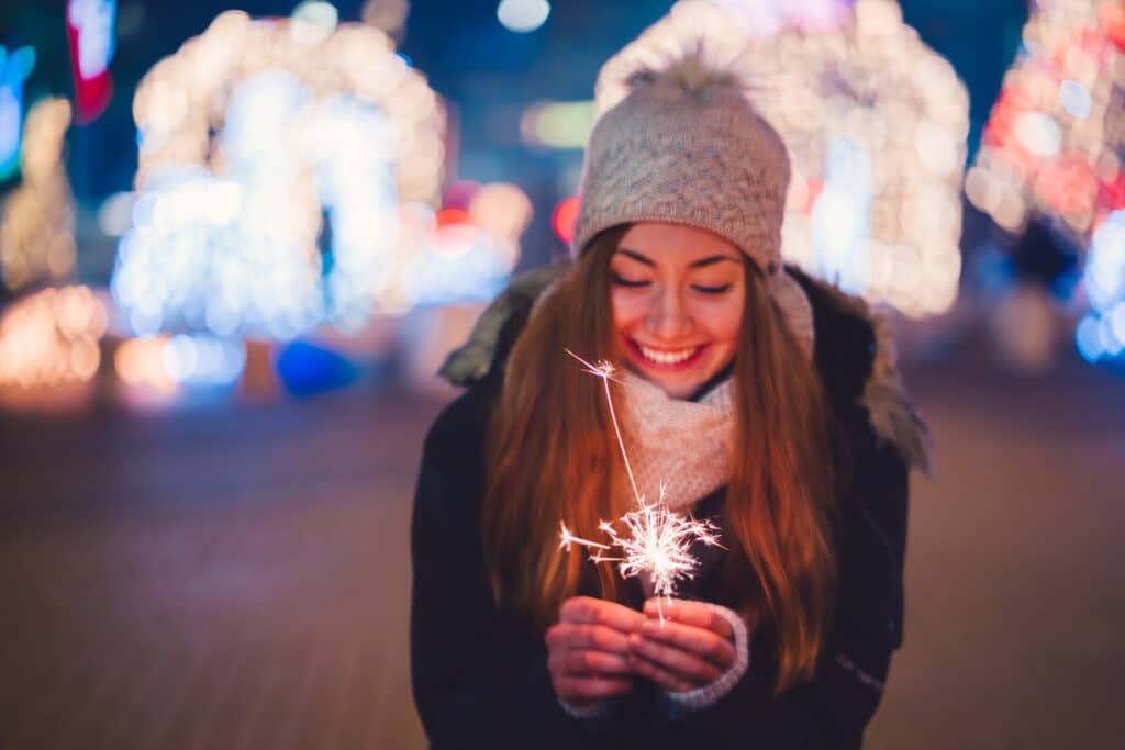 Happy woman at New Year's eve holding burning sparkler