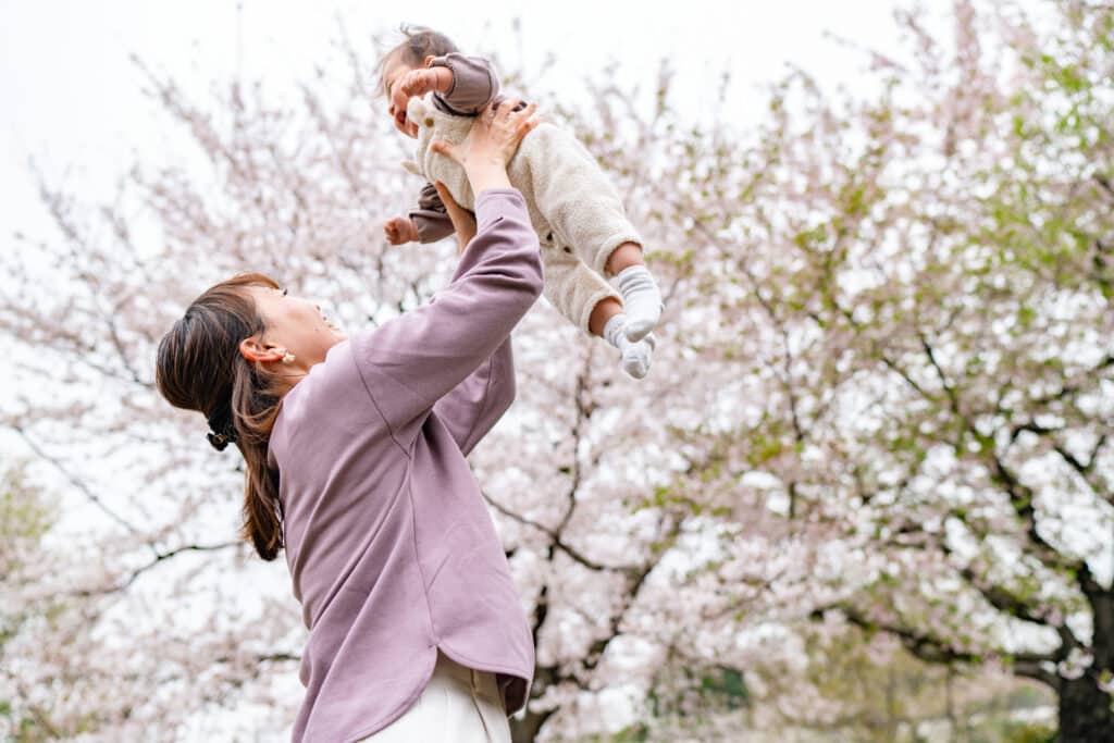 A mother and her small daughter are enjoying their time during spring time sakura cherry blossom trees season in nature.