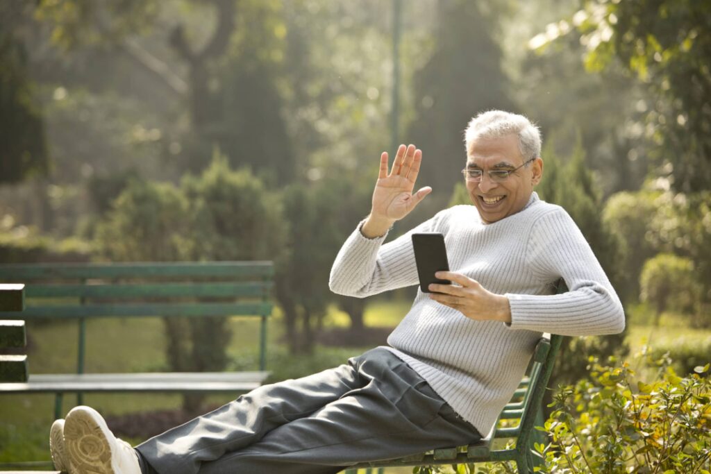 Senior man having fun using mobile phone at park