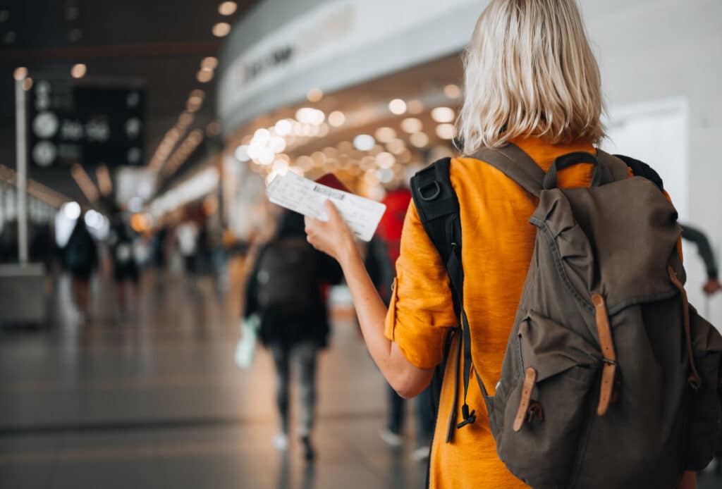 Rear view of a  woman at the airport holding a passport with a boarding pass as she walks to her departure gate