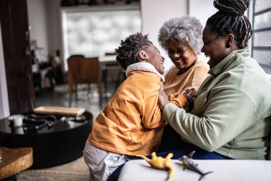 Child playing with his mother and grandmother in the living room at home